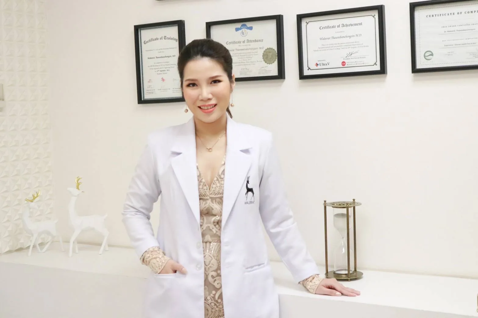 Dr. Gwang in her Waleerat Clinic white coat, with framed international training certificates on the wall — Bangkok